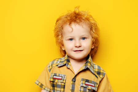 Portrait of a small three year old boy in summer clothes over yellow background. Copy space. Children fashion, summer concept. Happy childhood.の写真素材