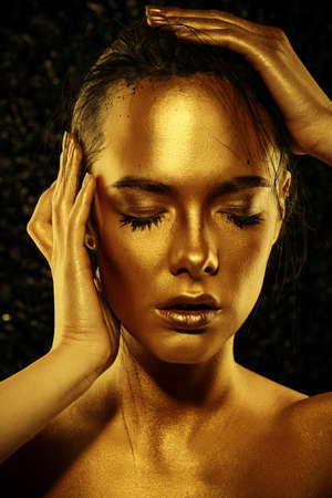 Beauty concept. Close-up portrait of a beautiful young woman with glowing golden skin. Skin care products, cosmetics. Jewellery concept.の写真素材