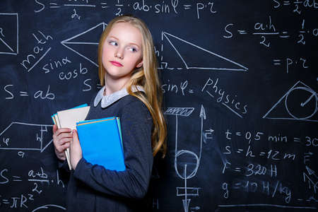 Smart student girl wearing black school dress standing by a blackboard.の写真素材