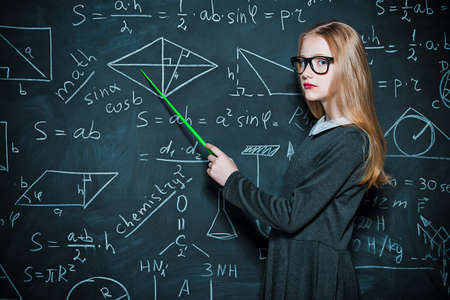 Smart student girl wearing black school dress standing by a blackboard.の写真素材