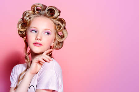 Portrait of a pretty girl teenager with curlers in her blonde hair.の写真素材