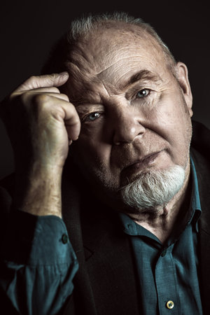 Portrait of old man over black background.