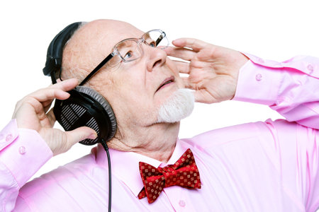 Portrait of a handsome old man listening to music in headphones. Isolated over white.