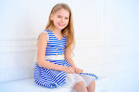 Cute little girl in a beautiful summer dress posing in a room with classical interior. Kid's fashion.の写真素材
