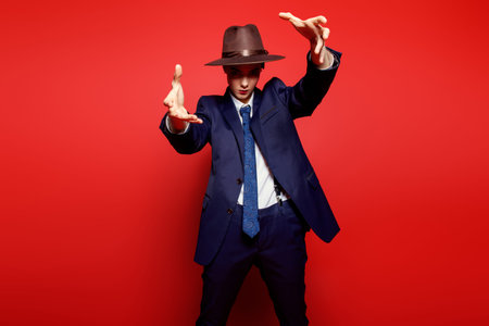 Portrait of an attractive young woman posing in a man's suit and a hat. Man's style clothing. Red...