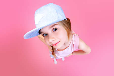 Close-up portrait of a funny emotional girl making faces at camera. Studio shot over pink background.の写真素材