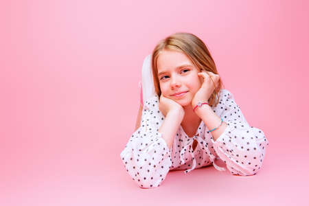 Cute eight year old girl wearing summer clothes posing over pink background. Studio shot.の写真素材