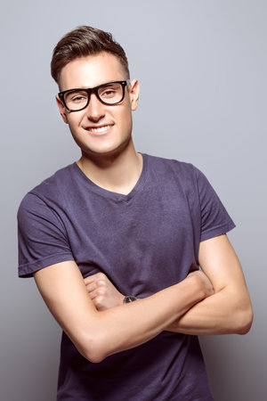 Portrait of a positive smiling young man in glasses. Studio shot.