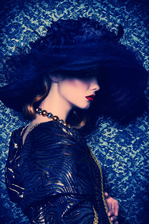 Fashion shot of a stunning young woman in luxurious dress and elegant hat over vintage background....