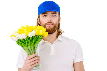 Handsome young man in blue cap and white t-shirt holding bouquet of tulips. White background.の写真素材