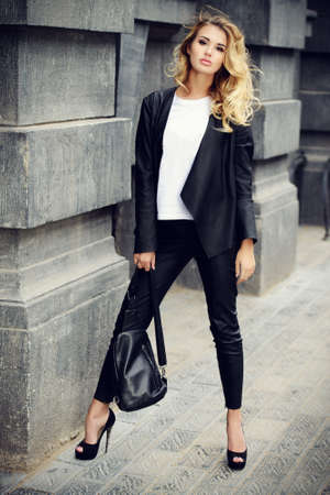 Fashionable woman wearing black leather clothes on a city street.の写真素材