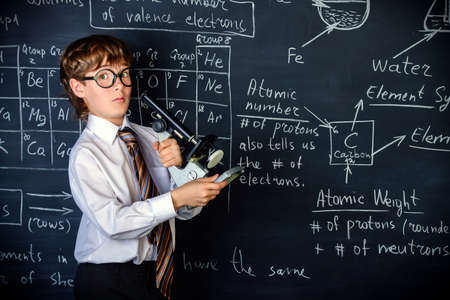 Serious schoolboy answering by a blackboard on a chemistry lesson. Educational concept.の写真素材