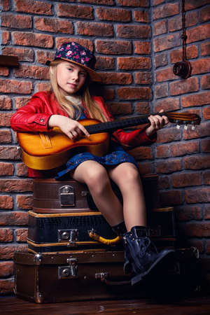 Modern child girl playing guitar and singing a song. Rock star, rock music, pop music concept.の写真素材