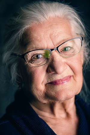 Portrait of a beautiful senior woman in elegant glasses smiling at camera.の写真素材