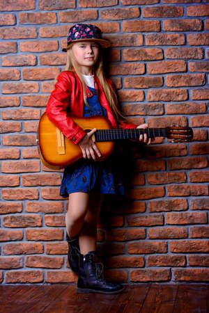 Modern child girl playing guitar and singing a song. Rock star, rock music, pop music concept.の写真素材
