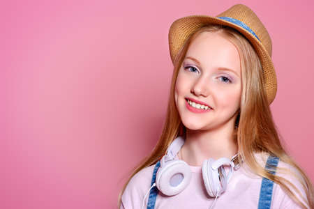 Teen's fashion. Portrait of a cute smiling girl teenager in summer clothes over pink background. Studio shot.の写真素材