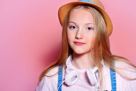 Teen's fashion. Portrait of a cute smiling girl teenager in summer clothes over pink background. Studio shot.の写真素材