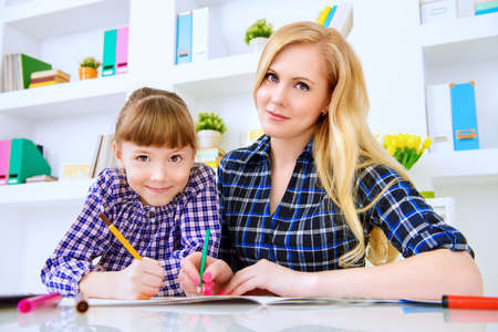 Happy family at home. Mother and daughter drawing and do lessons together. Education.の写真素材
