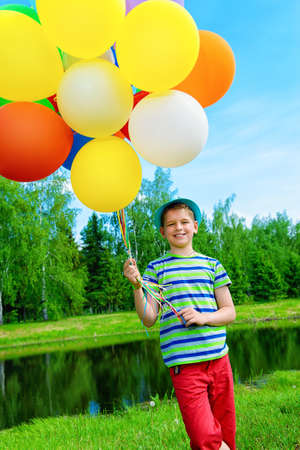 Happy boy enjoys with a sunny summer day and balloons. Summer holidays. Birthday.の写真素材