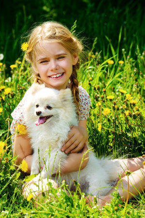 Cheerful girl embraces her lovely little dog. Sunny summer day in the countryside.の写真素材