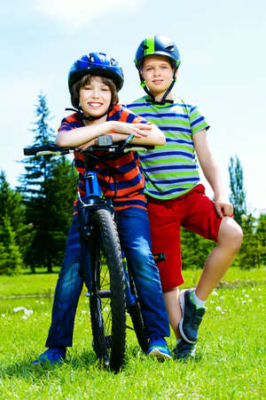 Happy boys are riding bikes in the park. Happy summer holidays.の写真素材