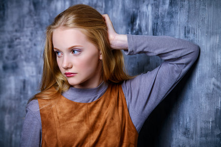 Teen fashion. Portrait of a cute girl teenager standing by a grunge wall.