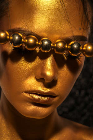 Beauty concept. Close-up portrait of a beautiful young woman with glowing golden skin. Skin care products, cosmetics. Jewellery concept.の写真素材