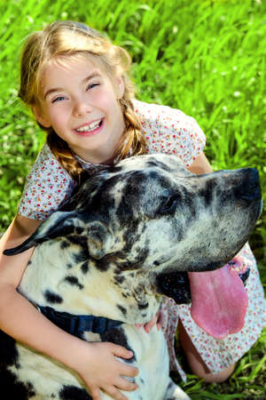 Happy little girl embracing her dog mastiff. Sunny summer day in the countryside.の写真素材