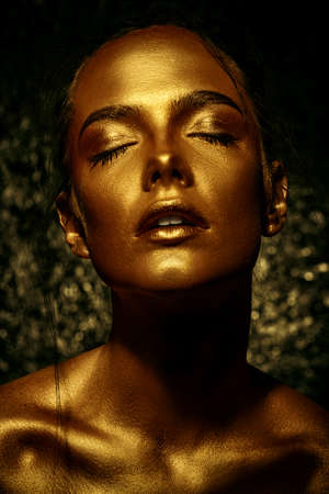 Beauty concept. Close-up portrait of a beautiful young woman with glowing golden skin. Skin care products, cosmetics. Jewellery concept.の写真素材