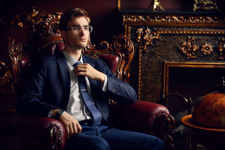 Handsome well-dressed young man in a room with classic interior. Business style. Luxury.の写真素材