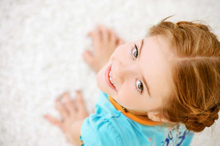 Joyful smiling child girl lying on a floor and having a rest at home. Happy childhood.の写真素材