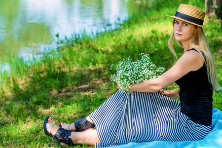 Portrait of a beautiful blonde woman relaxing under the tree in a summer park. Summer holidays, vacation.の写真素材