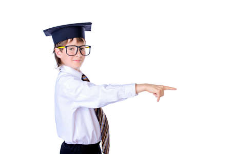 Portrait of a smiling student boy in glasses and academic hat showing at something. Educational concept. Isolated over white.の写真素材