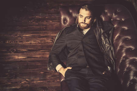 Portrait of a stylish handsome man on a leather sofa. Fashion shot. Men's clothing and accessories.の写真素材