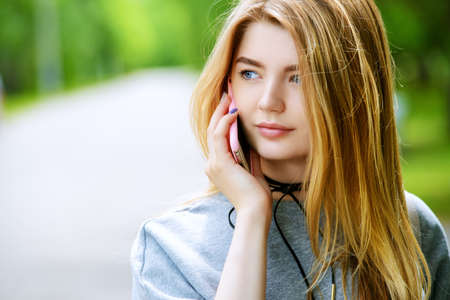 Modern teen girl talking on her cell phone on a city street. Beauty, fashion.の写真素材