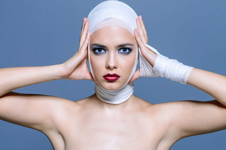 Close-up portrait of an attractive young woman in bandages. Beauty, fashion and medicine, plastic...