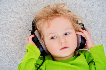 Little 3 year old boy listening to music in headphones.の写真素材