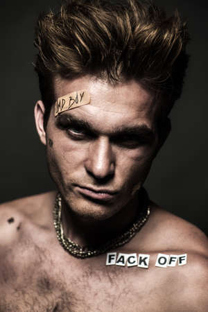 Bad boy concept. Close-up portrait of a bad guy showing rudeness and aggression. Rocker, punk.の写真素材