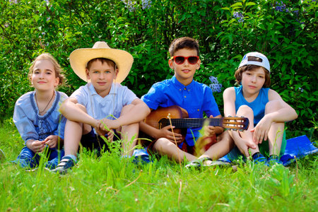 Group of cheerful children resting in the park with songs and guitar.