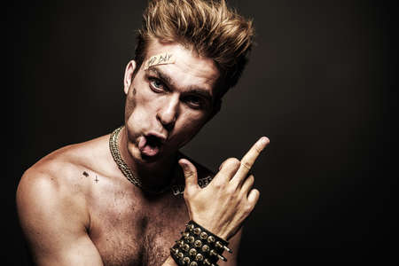 Bad boy concept. A portrait of a bad guy demonstrating antisocial behavior, rudeness and aggression. Rocker, punk.の写真素材