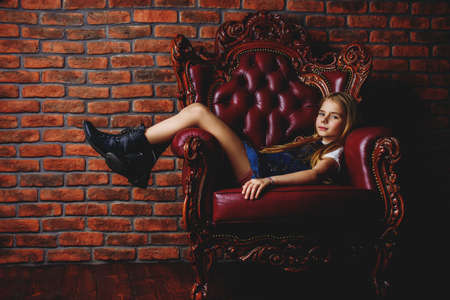 Children's fashion. Modern eight year old girl posing in vintage interior. Studio shot.の写真素材