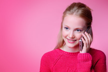 Cute girl teenager on her smartphone over pink background.