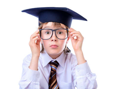 Portrait of a cute student boy in white shirt, a tie and academic hat. Educational concept. Isolated over white.の写真素材