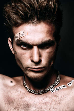 Bad boy concept. Close-up portrait of a bad guy showing rudeness and aggression. Rocker, punk.の写真素材