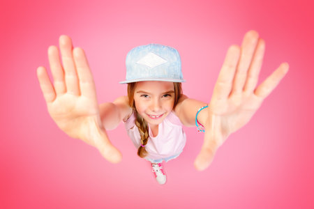 Close-up portrait of a funny emotional girl making faces at camera. Studio shot over pink background.の写真素材