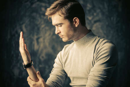 Portrait of a handsome young man looking at his hand. Male beauty. Men's health.の写真素材
