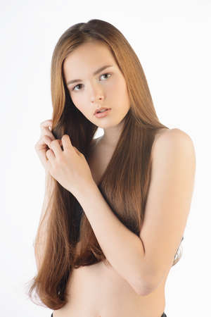 Young woman with natural makeup and beautiful long hair over white background.の写真素材