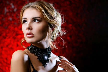 Charming young woman with evening make-up and hairstyle over red background.の写真素材