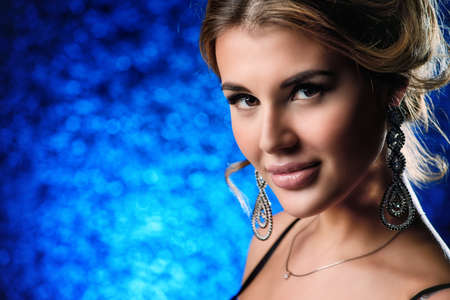 Beautiful young woman with evening make-up and hairstyle. Jewellery, earrings. Beauty and fashion concept.の写真素材