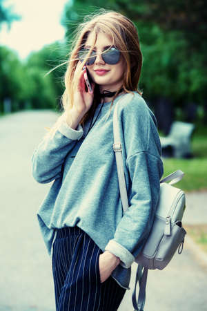 Teen style. Modern young girl with long blonde hair posing outdoor. Beauty, fashion.の写真素材